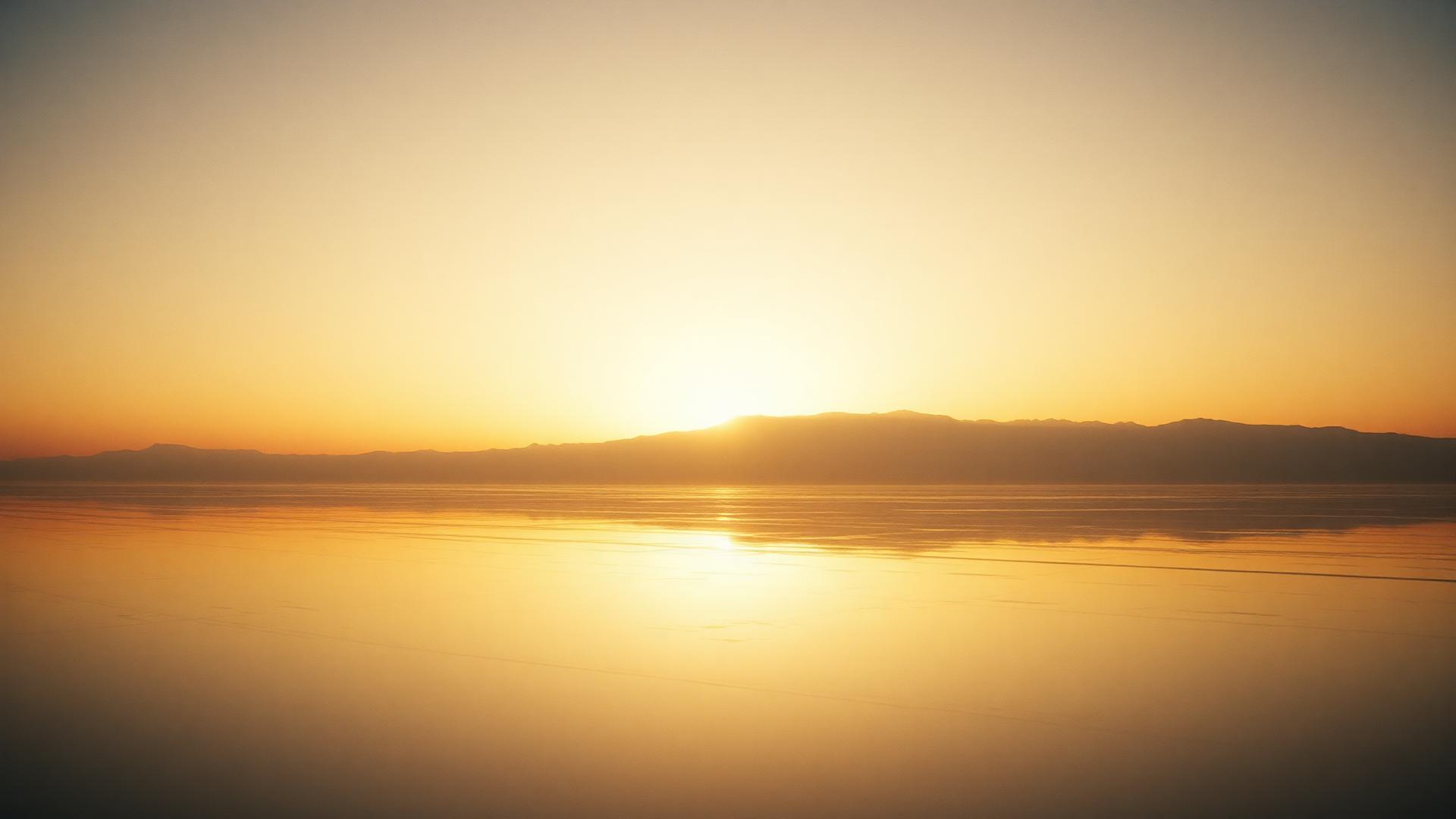 Dawn light breaking over a reflective salt-flat horizon.